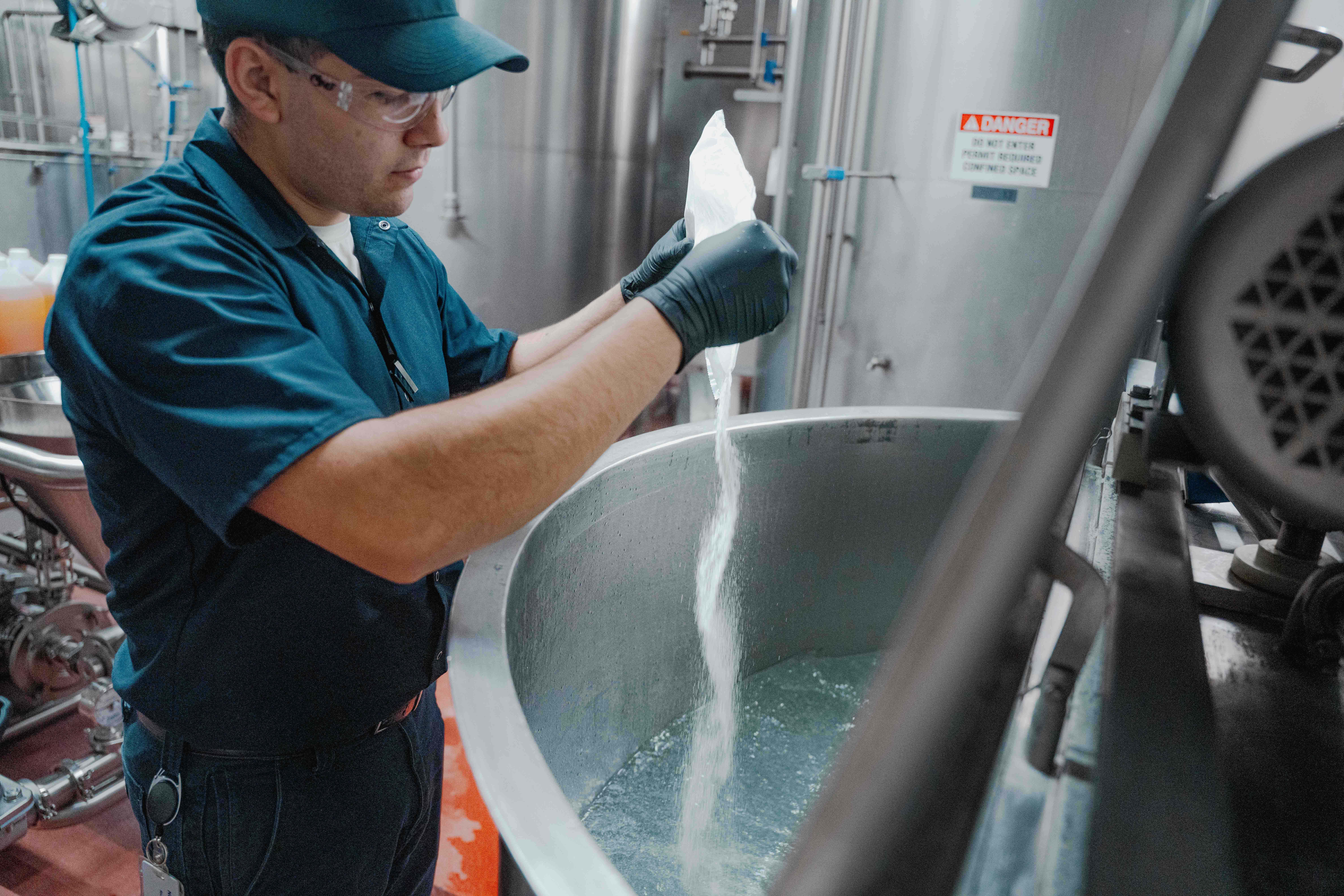 Person pouring powder into vat of liquid